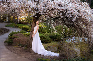 Young woman staying in wedding dress in park