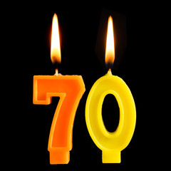 Burning birthday candles in the form of 70 seventy figures for cake isolated on black background. The concept of celebrating a birthday, anniversary, important date, holiday