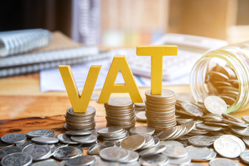 Vat Concept.Word vat with stacked coins there is a notebook calculator on the desk.VAT - obrazy, fototapety, plakaty