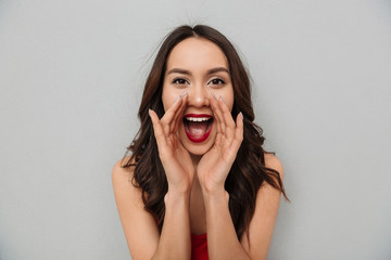 Cheerful brunette woman in casual clothes screaming