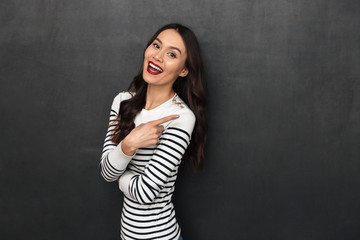 Cheerful brunette woman in sweater pointing away