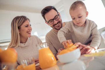 Obraz na płótnie Canvas Happy family making orange juice in their kitchen