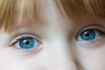 blue eyes of little blonde girl close up