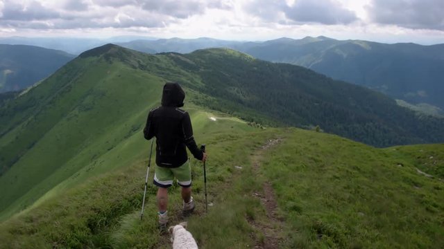 Young people with gogs Fox terrier hiking in mountains, travel, fitness or adventure concept outdoors in nature filmed with steadicam
