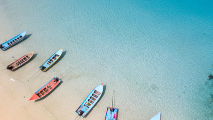 Aerial: Shoreline with thai fishing boats and long tail taxi boats parking along the sand beach of Thailand