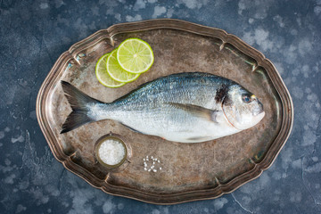 Fresh raw Dorado fish on a metal tray with ingredients for cooking, top view, horizontal