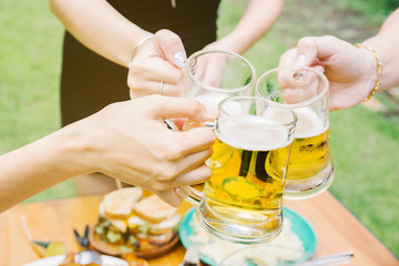 Close-up cropped image of friends clinking with beer in garden.
