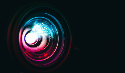 Photo depicts digital projector film presentation. Projector shiny colorful glass lens closeup, macro view, black background. - obrazy, fototapety, plakaty