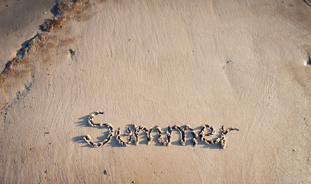 Inscription on wet sand Summer. Concept photo of summer vacation. A trip to the sea.