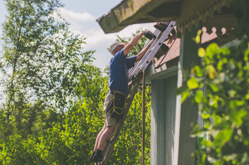 A man is repairing a roof standing on the stairs