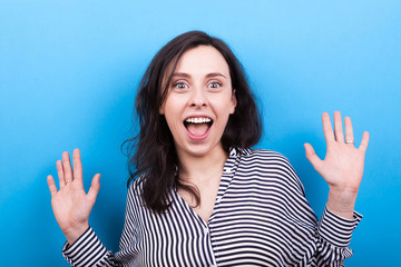 Beautiful young woman smiling with her teeth showing on blue background in studio