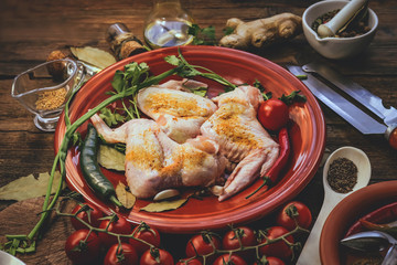 raw chicken wings. cooking. spices and vegetables. old kitchen accessories. wooden background