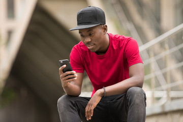 Young man in pink t-shirt use smart phone app in city street