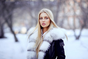 Young woman in fur coat standing outside