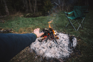 Traveler man warming his hands by the campfire outdoors