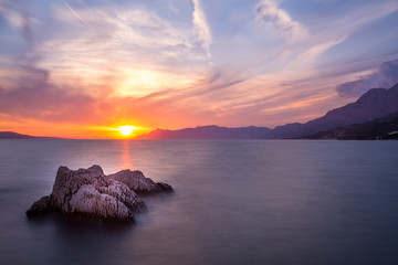 Langzeitbelichtung - Farbenfroher Sonnenuntergang mit Felsen, Gebirge und Wolken am Meer III © Michael