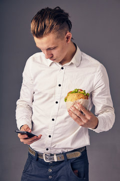 man eat hamburger in cafe while watch video on his phone