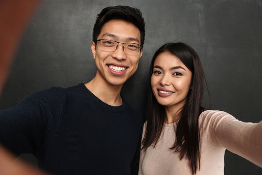 Happy asian couple posing together and making selfie