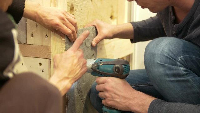 Hands of male carpenters working with the electric screwdriver