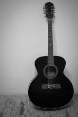 Fototapeta na wymiar Acoustic guitar in an empty room, black and white background
