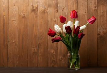 bouquet of tulips in a vase, wooden background