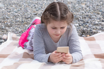 a girl with a phone on the beach on a Sunny day