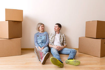 Fototapeta na wymiar Photo of young married couple sitting on floor among cardboard boxes