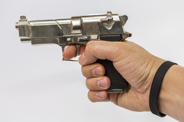 a male hand holds a toy gun that resembles a fighting weapon. gun toy in silver color.