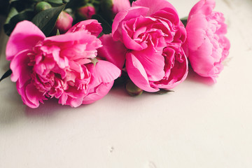 lovely pink peonies  on rustic white wooden background top view, space for text. floral greeting card mock-up. happy mothers day concept or valentines. beautiful spring image