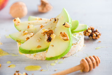 Easy crisp bread snack with pear slices, creamy cheese, honey and walnuts. Diet breakfast recipe in...