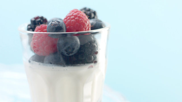 glasses with greek yogurt with berries Minimalism food on blue background. Panna cotta with strawberry raspberry, blueberry