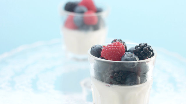 glasses with greek yogurt with berries Minimalism food on blue background. Panna cotta with strawberry raspberry, blueberry