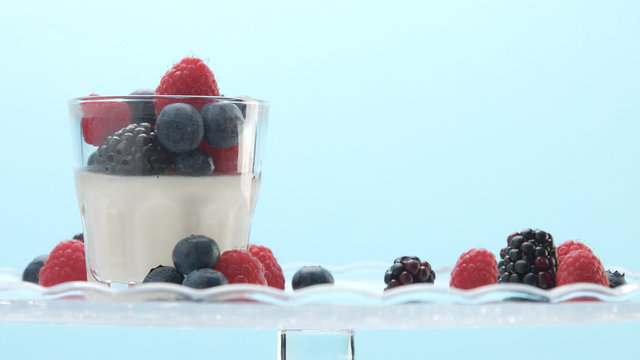 glasses with greek yogurt with berries Minimalism food on blue background. Panna cotta with strawberry raspberry, blueberry