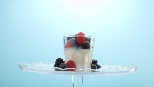 glasses with greek yogurt with berries Minimalism food on blue background. Panna cotta with strawberry raspberry, blueberry