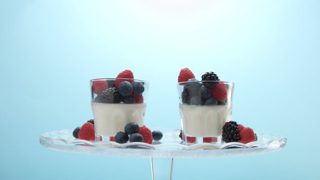 glasses with greek yogurt with berries Minimalism food on blue background. Panna cotta with strawberry raspberry, blueberry