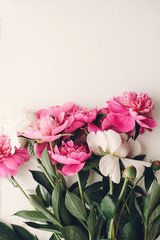 Fototapeta premium lovely pink peonies on rustic white wooden background, space for text. floral greeting card, flat lay. beautiful peony flowers, tender image. happy mothers or women day concept