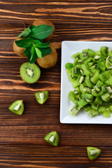 Freshly sliced kiwi fruit with whole kiwis in background.