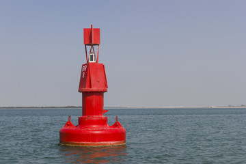 Floating red navigational buoy on blue sea