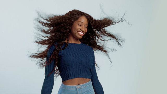 Beauty mixed race african american woman with hair blowed in air smiling at camera dancing Soft focus in movement