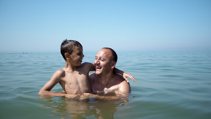 Father and son playing at beach together portrait fun happy lifestyle, boy embrace father and show victory successful gestures