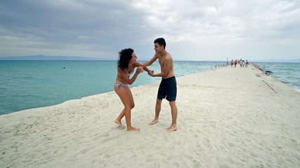 Young couple having fun fighting on the beach