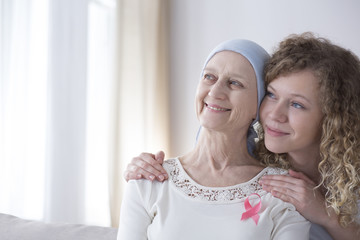 Smiling caregiver hugging senior woman