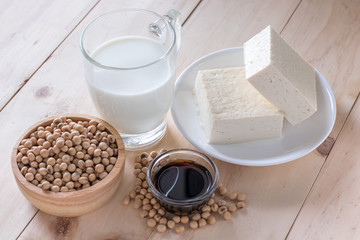 Food products including tofu, soy sauce and milk made from soybean on wooden background, natural source of protein for vegetarian
