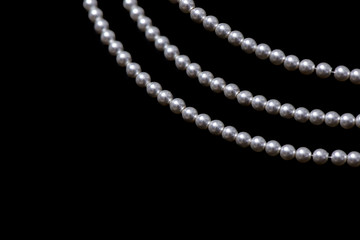 Three strings of pearls on black background.