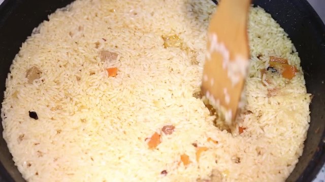 Preparation of rice dishes - pilaf from Uzbekistan. Rice is deepened in the rice to the very bottom.