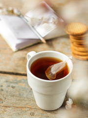 tea brew in a cup (tea bag) on ​​a wooden table and flowering spring twigs. Food background - drink background