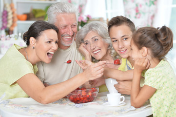 Obraz na płótnie Canvas Big happy family eating fresh strawberries at kitchen