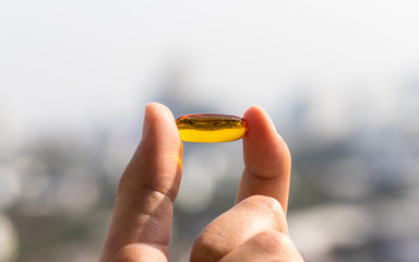Fish oil capsules in glass bottle on bokeh background, vitamin D supplement, selective focus