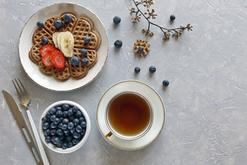  Pieces of homemade waffle cake with banana and blueberries on the plates on gray background. Top view, close up