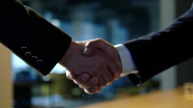 Businessmen shaking hands in office.